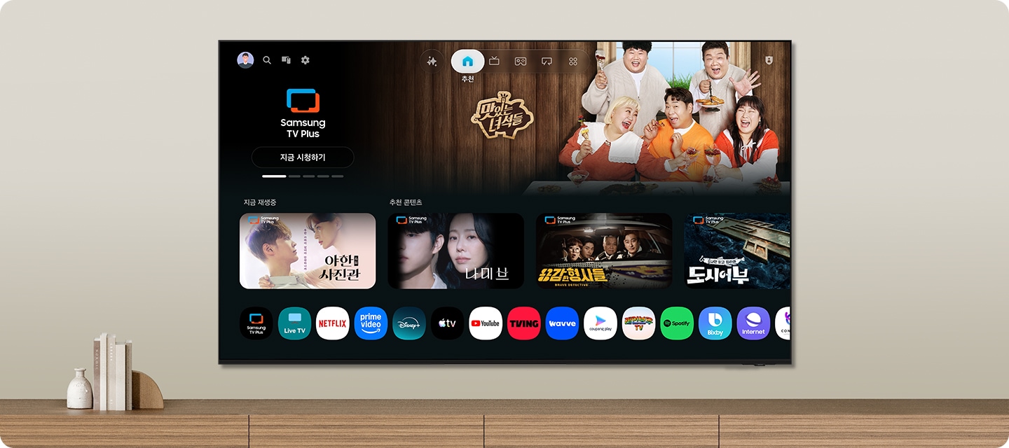 벽에 TV가 설치되어 있으며, 화면 속에는 여러 예능과 드라만 메인 화면이 보입니다.